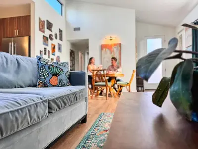a living room with a couch and people in a dining room at Newly Remodeled OB Beach house walk to all Parking in San Diego