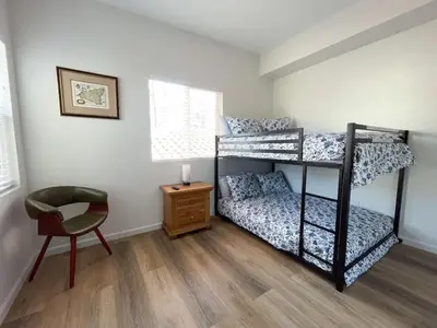a bedroom with two bunk beds and a chair at Harbor View Haven by Balboa Park in San Diego