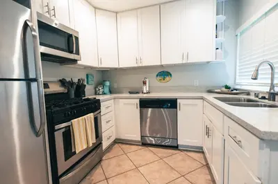 a kitchen with white cabinets and a stainless steel refrigerator at Mission Casa Del Sol in San Diego