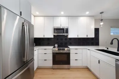 a kitchen with white cabinets and a stainless steel refrigerator at Spacious & Newly Renovated Villa in San Diego - Perfect for Families in San Diego