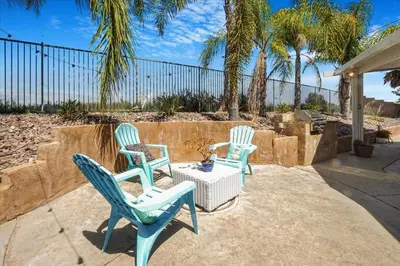 three chairs and a table on a patio with palm trees at Your Home Away From Home near Wineries & Old Town in Murrieta