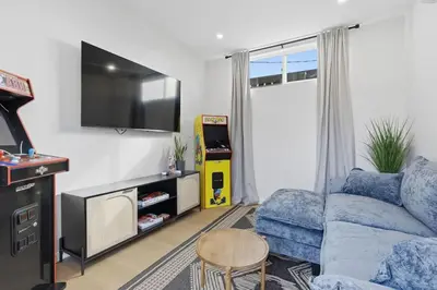 a living room with a blue couch and a tv at One Block to Beach 4BR Game Room and Parking in San Diego