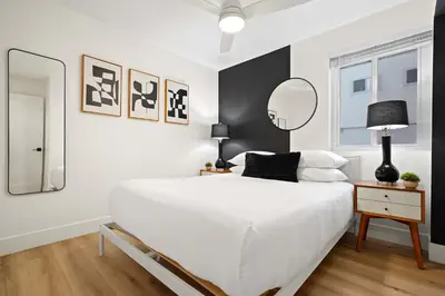 a bedroom with a white bed and a mirror at Explore South Park from 2-Story Home Sleeps 8 in San Diego