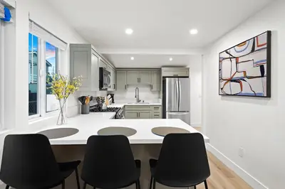 a kitchen with a white counter and black chairs at Explore South Park from 2-Story Home Sleeps 8 in San Diego