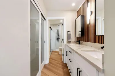 a white bathroom with two sinks and a shower at Bay View Penthauz Monthly Rental 2 parking spots in San Diego