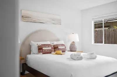 a white bedroom with a white bed with towels on it at Steps to Windnsea Beach | Parking, Patio, Location! in San Diego