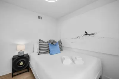 a white bedroom with a bed with a speaker at Steps to Windnsea Beach | Parking, Patio, Location! in San Diego