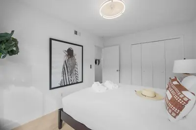 a white room with a bed and a chair at Steps to Windnsea Beach | Parking, Patio, Location! in San Diego