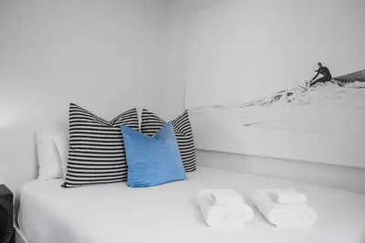 a white bed with pillows and a picture of a man on a mountain at Steps to Windnsea Beach | Parking, Patio, Location! in San Diego