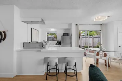 a white kitchen with a counter and a table at Steps to Windnsea Beach | Parking, Patio, Location! in San Diego