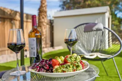 a table with a bowl of fruit and a bottle of wine at Sleeps 12 - Hot Tub - Pool - Game Room & Fire Pit! in Hemet