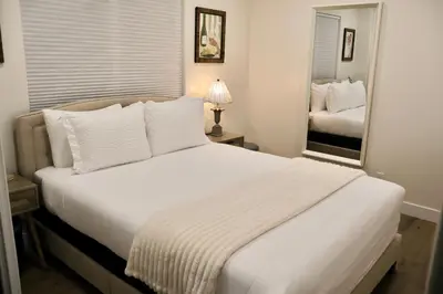a bedroom with a large white bed with a mirror at 2 Masters, Newly renovated with new furnishings - 4BR 3BA in San Diego