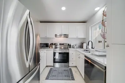 a kitchen with white cabinets and a stainless steel refrigerator at Jewell Street Gem - 3 properties in 1 in San Diego