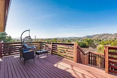 a wooden deck with a chair on top of it at Mountains Views with Pool & Basketball, Relax & Play! in Escondido
