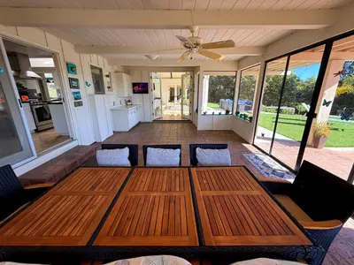 a screened in porch with a wooden table and chairs at Private Pickleball Villa, Pool Oasis & Chic Casita in Fallbrook