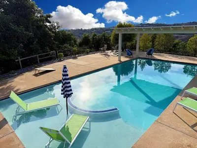 a large swimming pool with chairs and an umbrella at Private Pickleball Villa, Pool Oasis & Chic Casita in Fallbrook