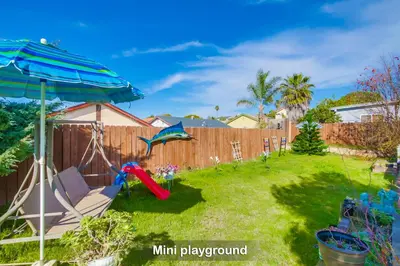 a backyard with a swing and an umbrella at Entire Private Home with 4 Bedrooms - 3 Bathrooms, Big Yard, Garage, King Bed, Crib, Available Now in San Diego