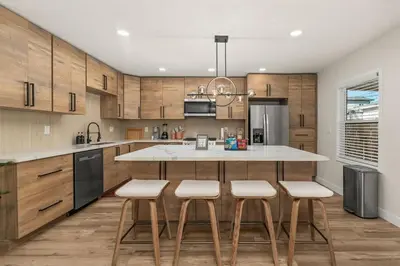 a kitchen with wooden cabinets and a kitchen island with stools at Palm Haven Retreat Cozy 2BR Near Downtown in San Diego