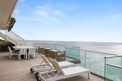 a balcony with tables and chairs and a view of the ocean at Encinitas Shores - Beachfront, Ocean View & Patio in Encinitas