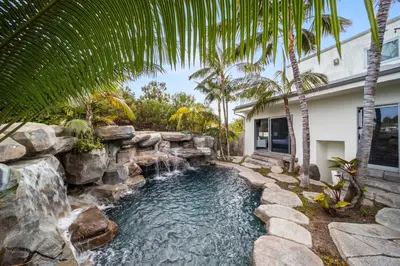 a backyard pool with a waterfall and a retaining wall at Encinitas Shores - Beachfront, Ocean View & Patio in Encinitas