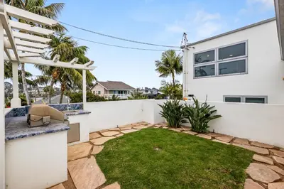 a backyard with a white fence and grass at Encinitas Shores - Beachfront, Ocean View & Patio in Encinitas