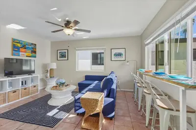 a living room with a blue couch and a bar at Beach Getaway Apt - Walk to Sand & Bay in San Diego