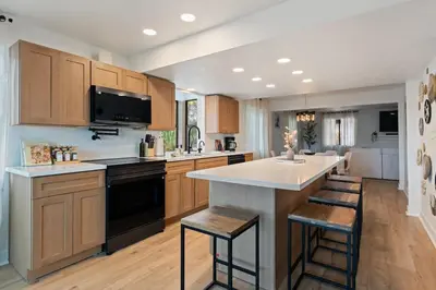 a kitchen with wooden cabinets and a large island with bar stools at Villa Tierra Alta - Pool, Spa, Movie Theater, Game Room in La Mesa