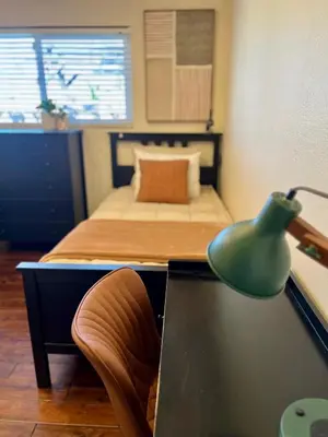 a bedroom with a bed and a desk with a green lamp at Granite Hills Sunset Villa in El Cajon