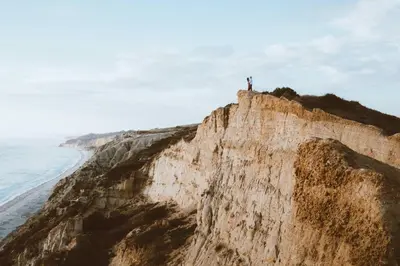 a man standing on the edge of a cliff near the ocean at Entire Private Home with 2 Bedrooms 1 Bathroom, Gated Yard, Driveway Parking, Available Now in Spring Valley