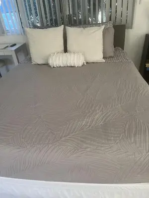 a large bed with a gray comforter and pillows at Redwing in San Marcos
