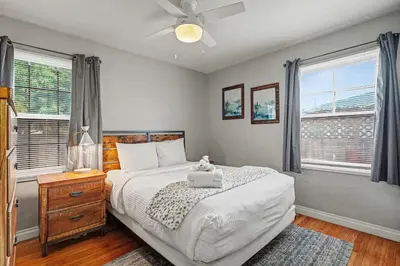 a bedroom with a bed with a ceiling fan and windows at Charming La Mesa Cottage - Patio - Quiet Neighborhood - Family in La Mesa