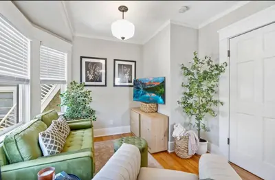 a living room with a green couch and some plants at The Downtown Carraige Flat in San Diego