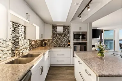 a kitchen with white cabinets and marble counter tops at Sunset on Sail Bay - Beautiful 2 Bedroom Condo in San Diego