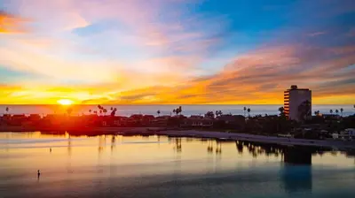 a sunset over a city with the ocean and a city at Sunset on Sail Bay - Beautiful 2 Bedroom Condo in San Diego
