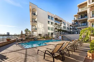 an apartment patio with a swimming pool and chairs at Sunset on Sail Bay - Beautiful 2 Bedroom Condo in San Diego