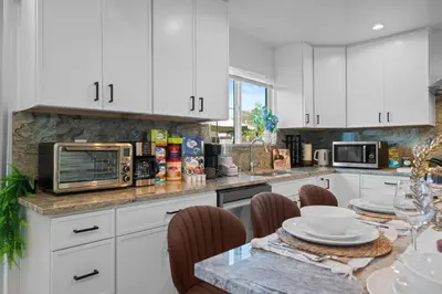 a kitchen with white cabinets and a table with a microwave at Entire Private Home with 3 Bedrooms 2 Bathrooms, with Garage, Gated Yard, King Bed House, Available Now in El Cajon
