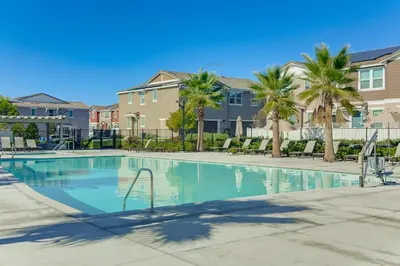 a swimming pool with palm trees and condos at Family Getaway with Pool, 8 Mi to Lake Elsinore! in Wildomar