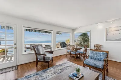 a living room with a table and chairs and windows at Oceanfront St Anns Beach Laguna Beach Private Beach Stairs To The Sand in Laguna Beach