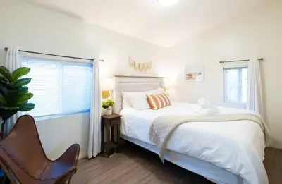 a white bedroom with a bed and a window at Boho Chic Cottage Walk to Cafes Outdoor Lounge in San Diego