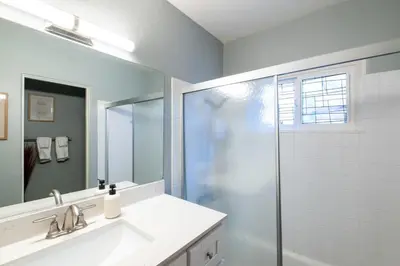 a bathroom with a shower and a sink and a mirror at Boho Chic Cottage Walk to Cafes Outdoor Lounge in San Diego