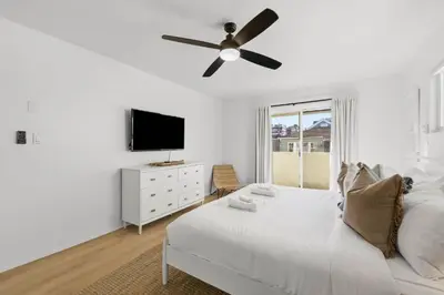 a white bedroom with a bed and a ceiling fan at Remodeled 4BR Bayfront Home | Sleeps 12 | Stunning Views + BBQ Patio in San Diego