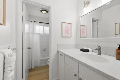 a white bathroom with a sink and a mirror at Remodeled 4BR Bayfront Home | Sleeps 12 | Stunning Views + BBQ Patio in San Diego