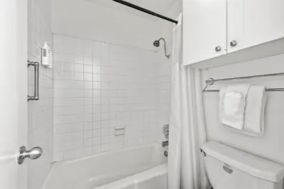 a white bathroom with a tub and a toilet at Remodeled 4BR Bayfront Home | Sleeps 12 | Stunning Views + BBQ Patio in San Diego