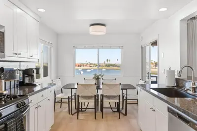 a kitchen with white cabinets and a table with chairs at Remodeled 4BR Bayfront Home | Sleeps 12 | Stunning Views + BBQ Patio in San Diego