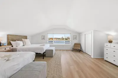 a white bedroom with two beds and a window at Remodeled 4BR Bayfront Home | Sleeps 12 | Stunning Views + BBQ Patio in San Diego