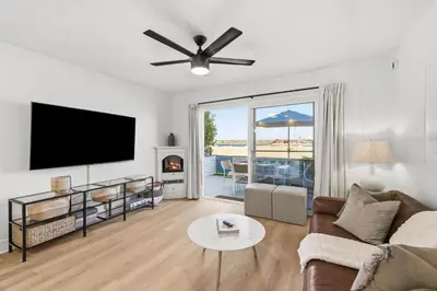 a living room with a couch and a flat screen tv at Cozy 2BR Bayfront Home | Patio + Water Views in Mission Beach in San Diego