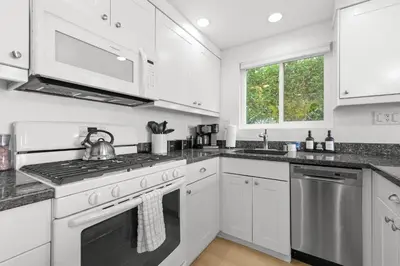 a kitchen with white cabinets and a stove top oven at Cozy 2BR Bayfront Home | Patio + Water Views in Mission Beach in San Diego