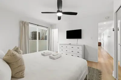 a white bedroom with a bed and a television at Cozy 2BR Bayfront Home | Patio + Water Views in Mission Beach in San Diego