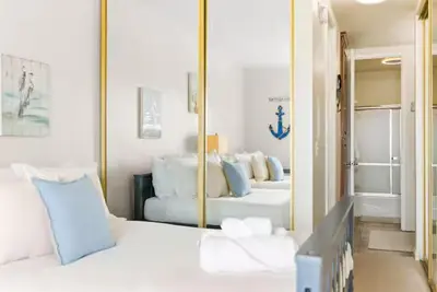 a bedroom with a mirror and a white bed at Beachfront Resort-sunset views deck & luxe king in Oceanside
