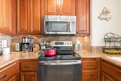 a kitchen with a stove and a microwave at Beachfront Resort-sunset views deck & luxe king in Oceanside